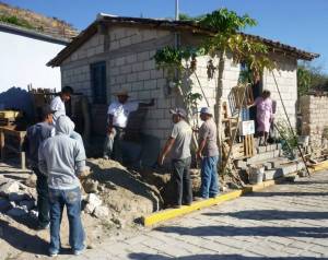 Our happy recipient at the top of her horrible stairs and the team of workers connecting her to the water supply